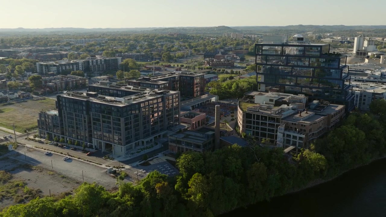 Ampia ripresa aerea fluida con drone catturata sul fiume Cumberland all'ora d'oro, incentrata sul quartiere Newhoff Germantown a nord di Nashville