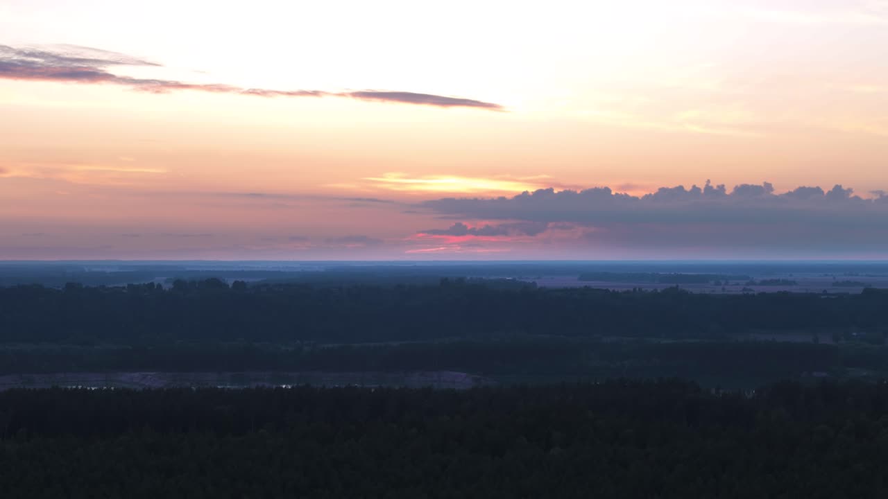 Orange sky with cloudscape above flatlands of Lithuania, aerial view