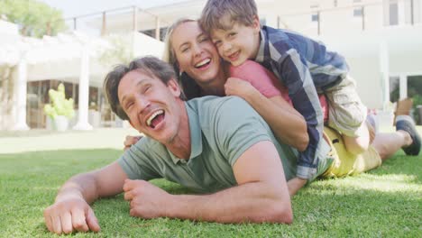 retrato de una feliz pareja caucásica con un hijo acostado en el jardín