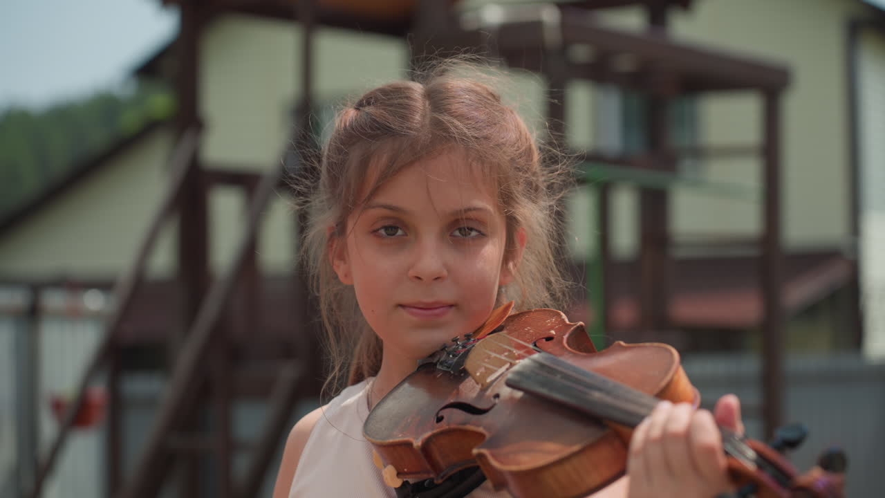 White Girl Practicing Violin Near Playground, Suburban Backdrop With Climbing Frame And Houses, Casual Outdoor Lesson, Poised Bowing, Youthful Determination And Summertime Atmosphere
