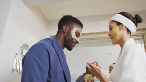 pareja feliz diversa haciendo maquillaje y mirándose el uno al otro en el baño