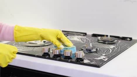 cleaning kitchen gas stove. womans hand cleaning gas stove with sponge