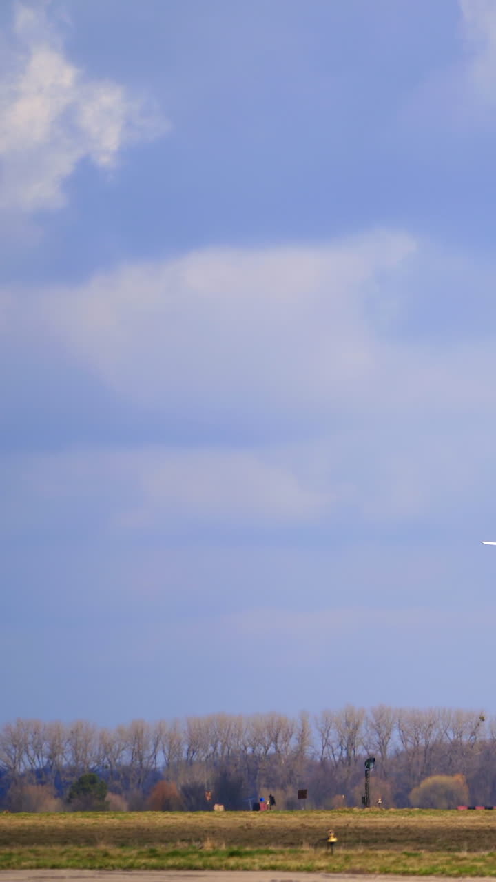 White little plane is rising in the air. Aircraft is flying above the field in autumn. Vertical video