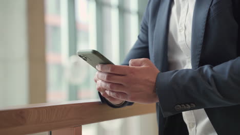 The-Hands-Of-A-Businessman-In-A-Blue-Blazer-Consults-His-Smart-Phone-And-Write-On-It