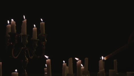 lighting of a group of white candles some on a candelabra lit up and running for a while