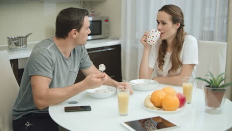 Smiling-couple-eating-healthy-breakfast-together-at-modern-kitchen.