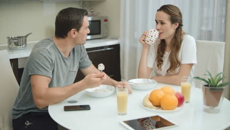 smiling couple eating healthy breakfast together at modern kitchen.