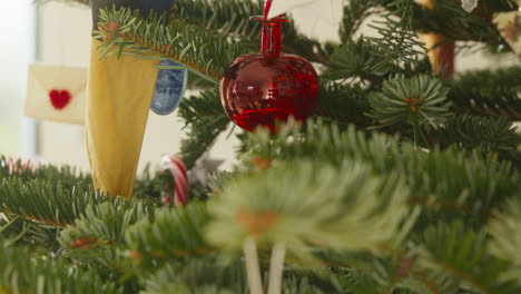 red christmas bauble hanging on a decorated fir tree