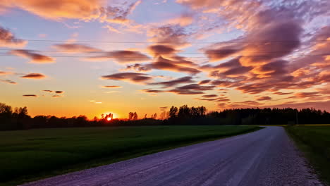 dramatic vivid sunset over country road with glowing clouds and orange sky layers