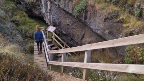 control deslizante, la persona desciende las escaleras a la cueva de luxmore, viaje lateral a la pista de kepler, nueva zelanda