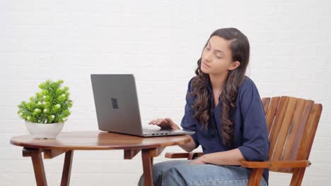 chica india cansada trabajando en una computadora portátil