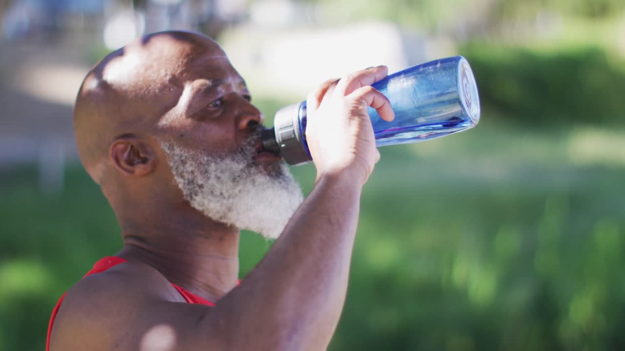 Senior african american man exercising taking a break drinking water