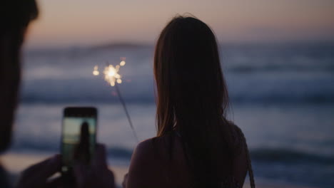 portrait of beautiful young woman holding sparkler posing for photo on romantic sunset beach celebrating new years eve