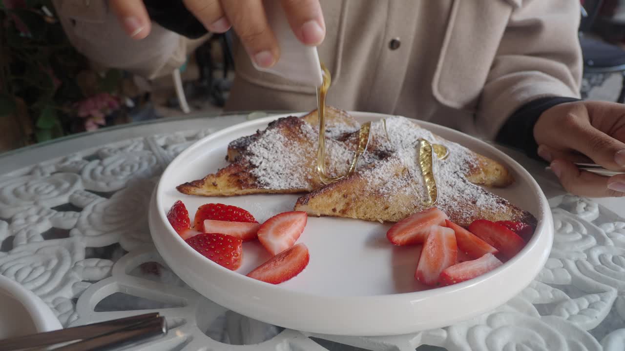 Woman enjoying French Toast with Strawberries and Honey