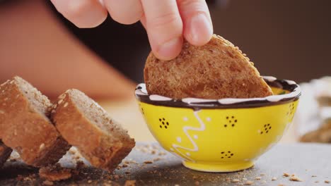 hand dipping bread in honey dip