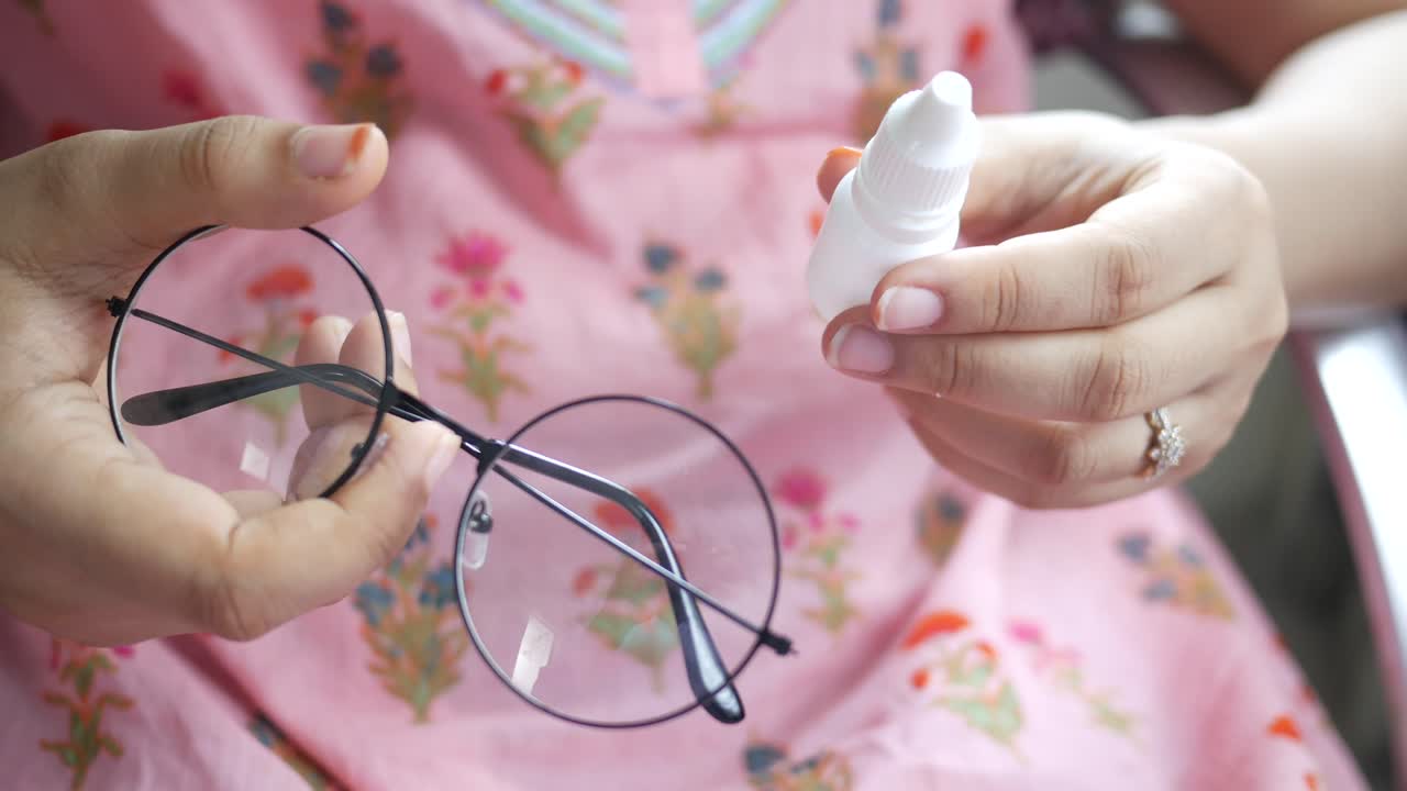 mujer limpiando sus gafas con gotas para los ojos
