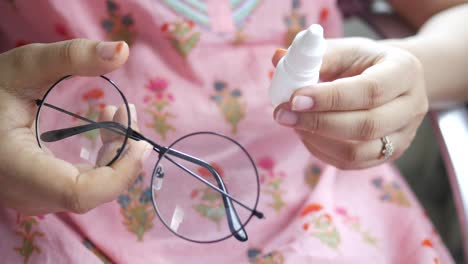 woman cleaning her eyeglasses with eye drops