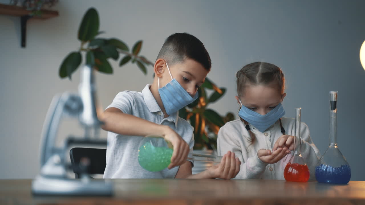 niños y ciencia. niño y niña usando máscaras faciales con cristalería de laboratorio.