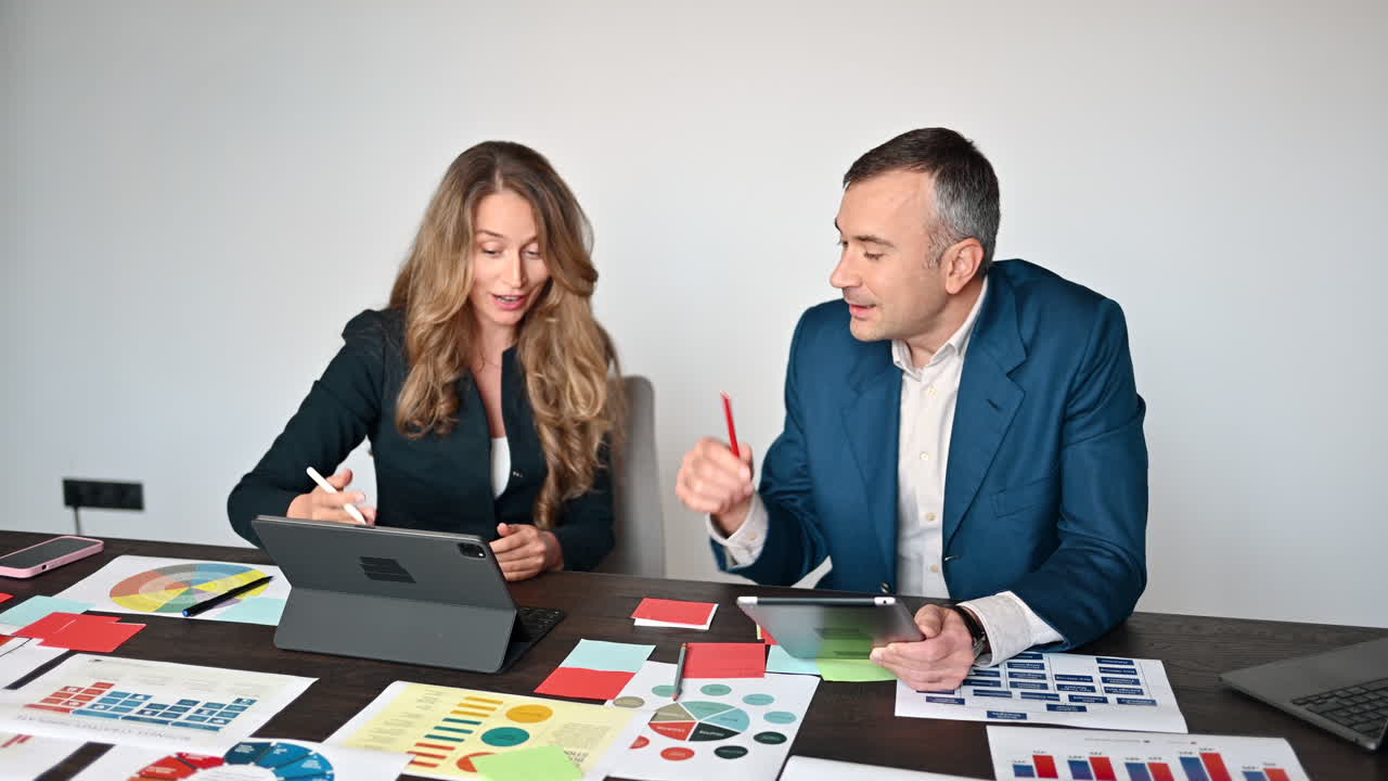 Coworkers talking while pointing at a tablet in an office