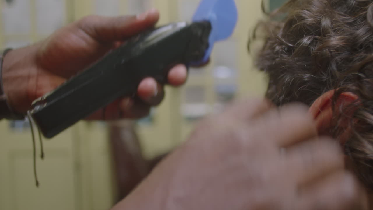 Hands of Barber Trimming Neckline of Client with Hair Clippers