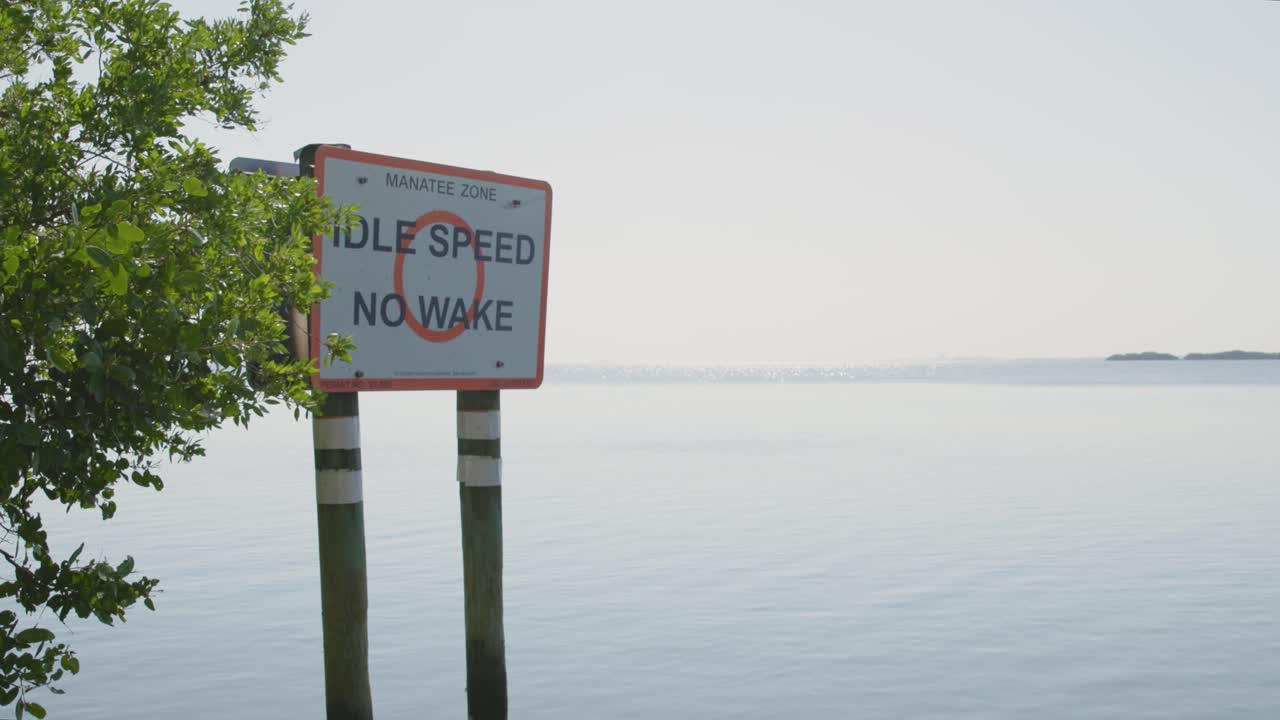 Shot of an "Idle Speed" sign next to tree in the ocean at Biscayne National Park, Florida. Calm waters and clear skies make this ideal for marine, boating, or nautical projects