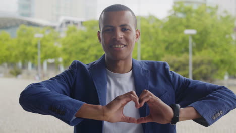 hombre afroamericano sonriente haciendo el signo del corazón con las manos
