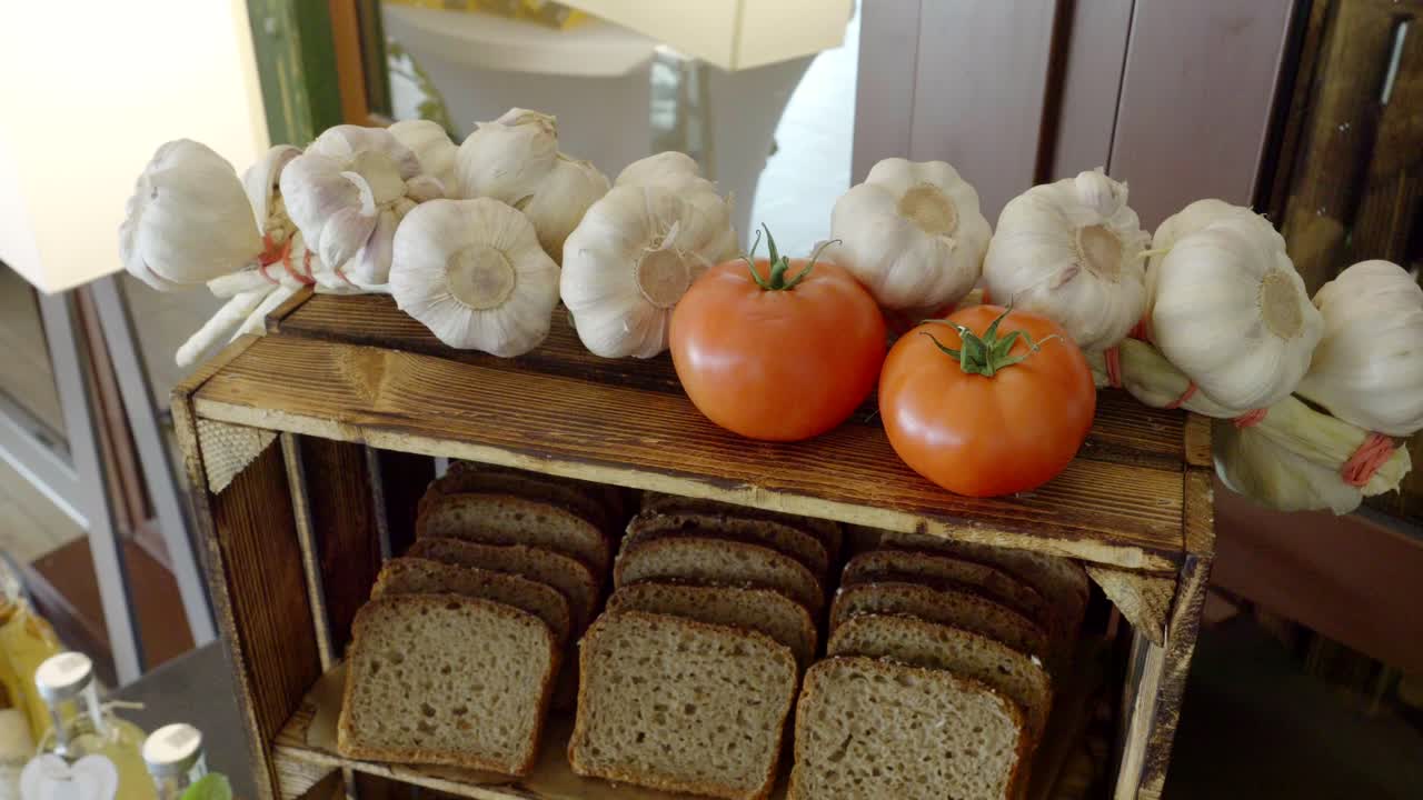 Rural table made from a wooden crate, on which there are tomatoes, garlic, and bread