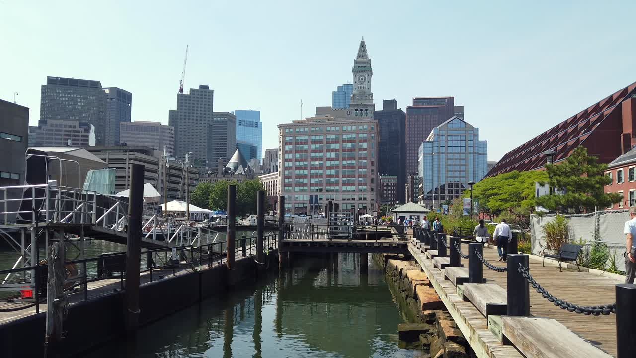 Boston, Massachusetts - September 20, 2021: Visitors stroll along the waterfront in Boston, enjoying the bright weather and beautiful city skyline. The area is lively with people and scenic views of the harbor