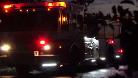 dynamic shot using the foreground of leaves and the background of a firetruck with its lights on after a storm with reflections not he ground and a warm sunset behind it after a tornado in ottawa