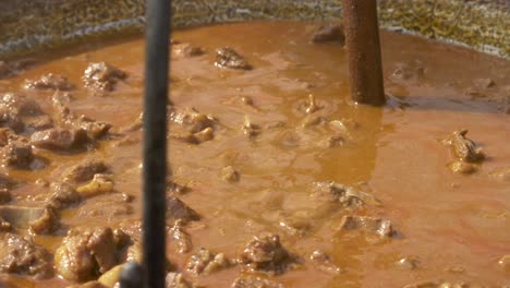 Boar-stew-boiling-in-a-rotating-cauldron-over-fire---180-fps-slow-motion