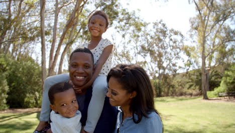 happy mixed race family together in a park looking to camera