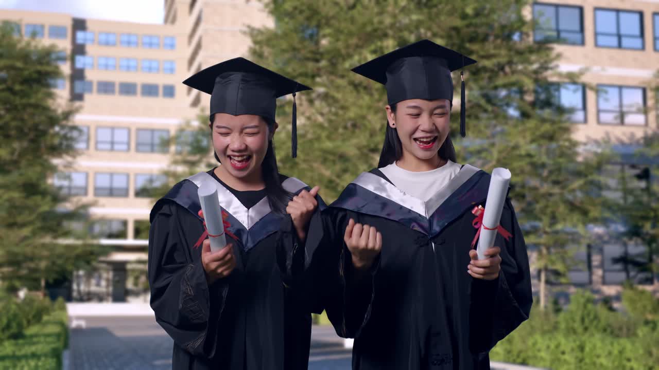 アジア系の女性学生が帽子とガウンを着て卒業証書を持ち壮大な大学建物の前で卒業式を祝いながら叫んでいます