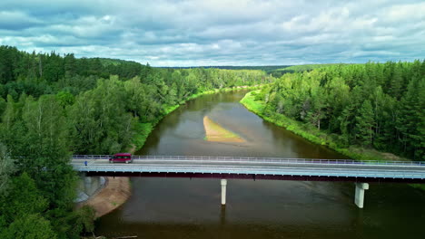 newly constructed bridge over a river and forested countryside - pullback aerial reveal