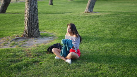 una hermosa joven hispana en un parque tratando de calentarse y ponerse cómoda con su suéter en el clima ventoso de la estación fría