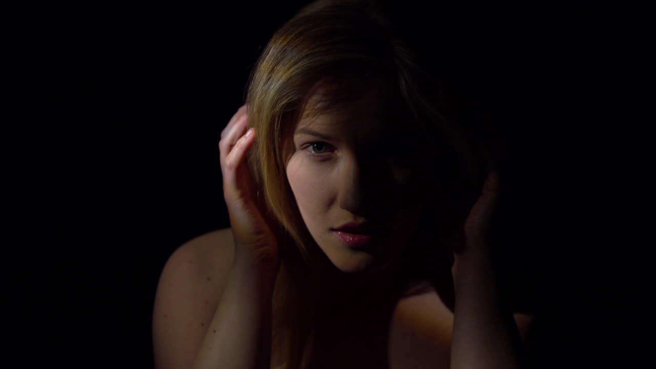 Seductive woman. The face of a smiling woman in twilight on a black background. The eyes and mouth are visible. Concept of sexuality and desire