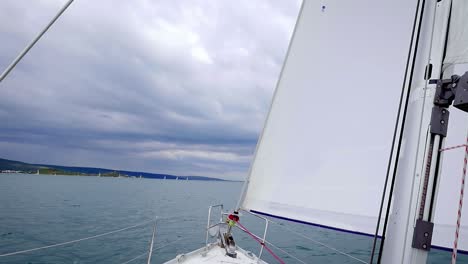 View-Of-Headsail-And-Mast-Of-A-Sailboat-Sailing-On-The-Calm-Blue-Sea---panning-down-shot