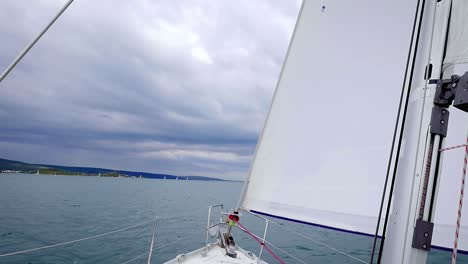 Blick-Auf-Vorsegel-Und-Mast-Eines-Segelboots,-Das-Auf-Dem-Ruhigen-Blauen-Meer-Segelt---Schwenk-Nach-Unten