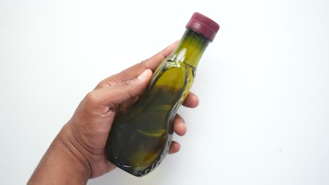 a hand holding a bottle of olive oil