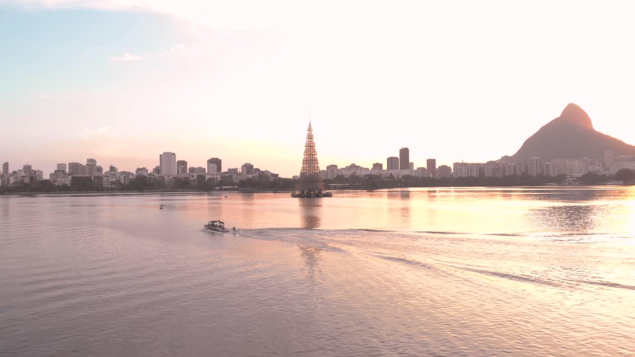 2018년 리우데자네이루에서 세계에서 가장 높은 떠다니는 크리스마스 트리가 있는 풍경, 쾌속정과 수상 스키어가 지나가는 풍경, 놀라운 일몰, 그리고 뒤쪽에 있는 두 형제의 산