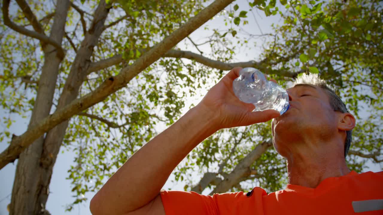 vista de bajo ángulo de un entrenador masculino bebiendo agua en el jardín de un asilo de ancianos 4k