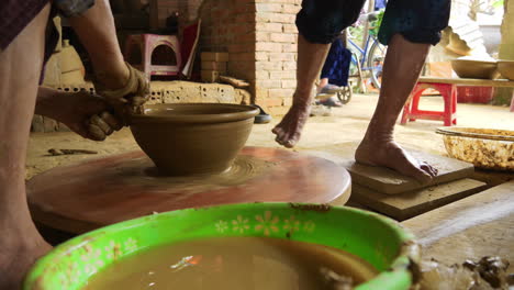 skilled hands turning traditional vietnam pottery on a foot-powered table, molding clay with precision and care