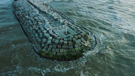 Aerial-birdseye-view-of-protective-stone-pier-with-concrete-blocks-and-rocks-at-Baltic-sea-coastline-at-Liepaja,-Latvia,-strengthening-beach-against-coastal-erosion,-drone-shot-moving-forward