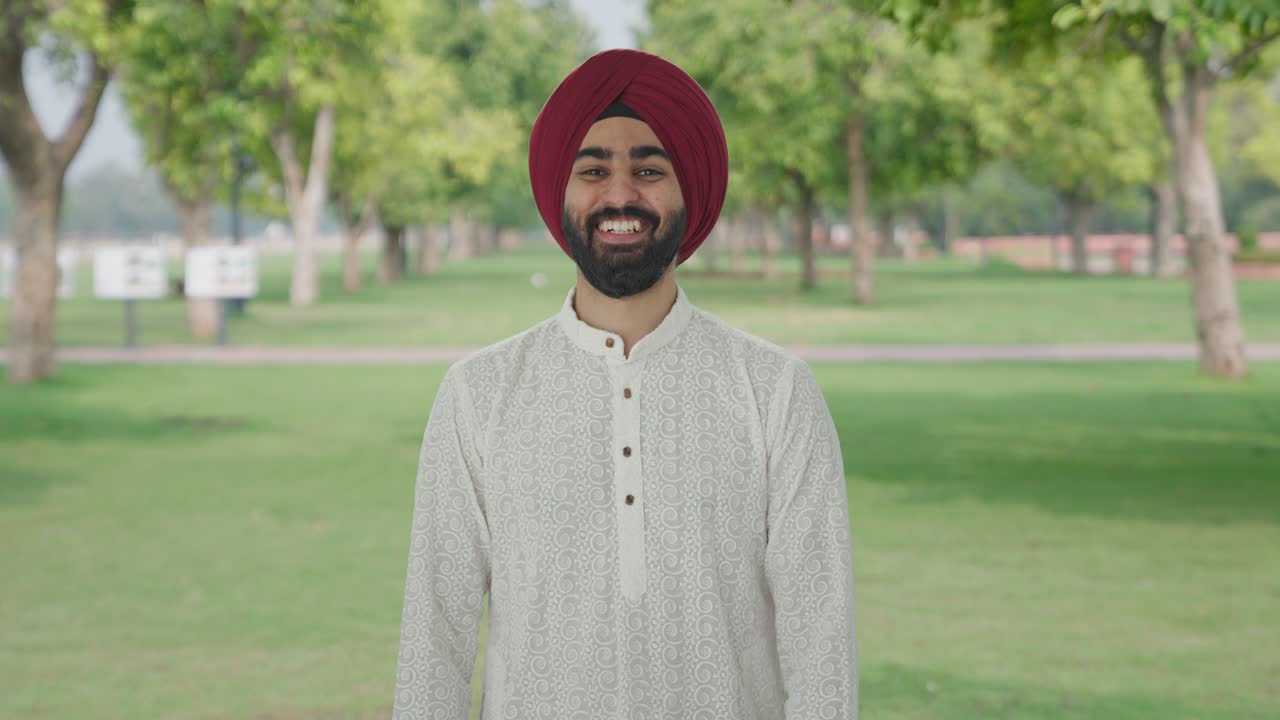 Uomo indiano Sikh felice che ride con qualcuno al parco