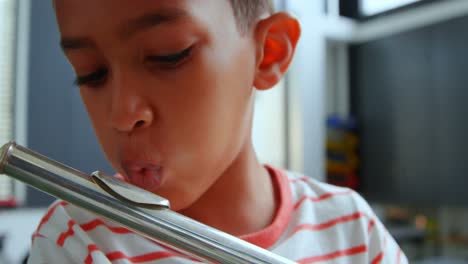 Front-view-of-attentive-Asian-schoolboy-playing-flute-in-classroom-at-school-4k