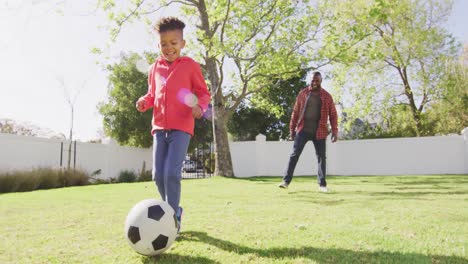 Happy-african-american-father-and-his-son-playing-football-in-garden