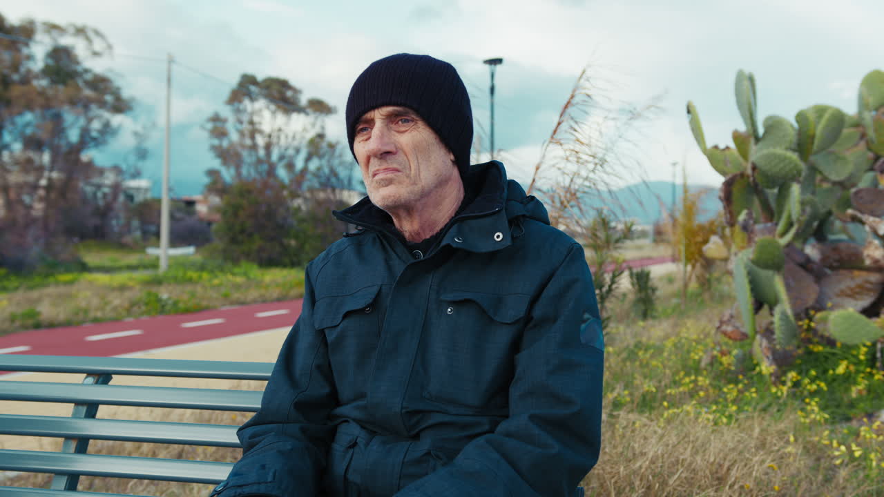 Elderly Man Relaxing Sitting on a Bench in Winter