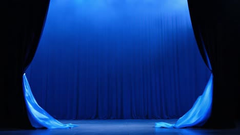 a stage with a blue curtain and spotlight