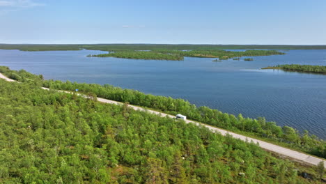 Vista-Aérea-De-Una-Autocaravana-Conduciendo-Por-El-Lago-Inari-En-Laponia,-Norte-De-Finlandia