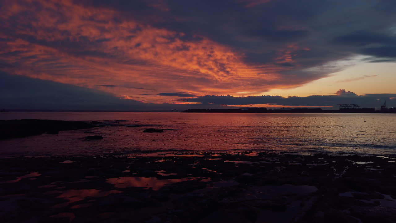 los colores calientes en llamas iluminan el cielo nublado sobre aguas tranquilas cerca del puerto de sydney
