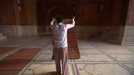 man shaking dust out of prayer mats